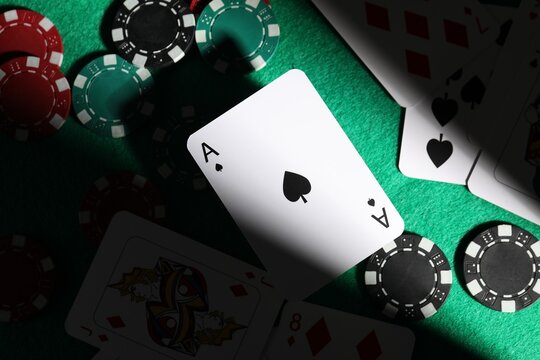 Casino chips and playing cards on green table, flat lay