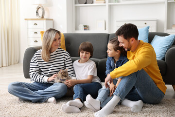 Happy family with their cute cat at home. Adorable pet © New Africa