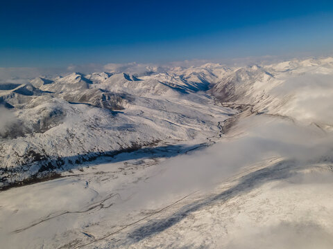 Aerial view of Babusar Pass with snow-covered mountain peaks and a winding road through the valley under a clear blue sky Babusar, KPK, Pakistan.