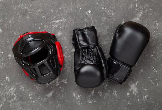 Boxing helmet and gloves on concrete background, top view.