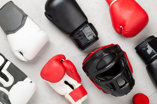 Boxing helmet and gloves on concrete background, top view.
