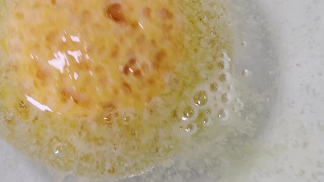 Closeup orange bath bomb spinning and fizzing bubbles