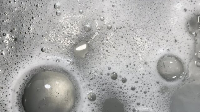 Foamy bubbles swirl and pop in sink