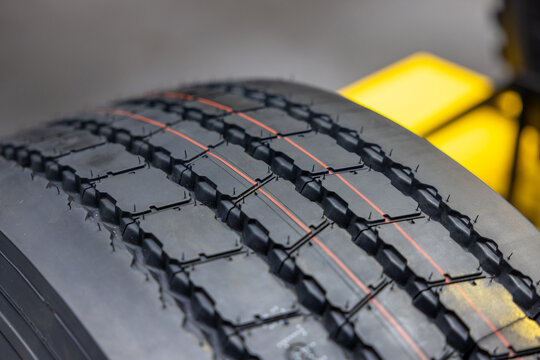 Close up of new truck tire tread pattern with red safety lines. Professional heavy duty commercial vehicle rubber texture for all weather road traction. Automotive logistics equipment