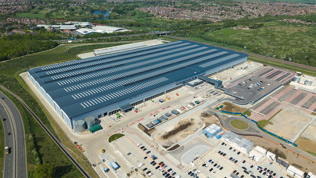 Aerial view of Symmetry Park logistics center featuring a massive warehouse with solar panels and extensive parking facilities in Kettering, England, United Kingdom.