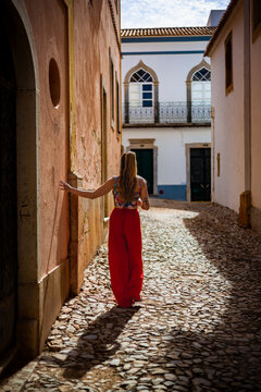Young woman walking on historic cobblestone street in Estoi village, Algarve