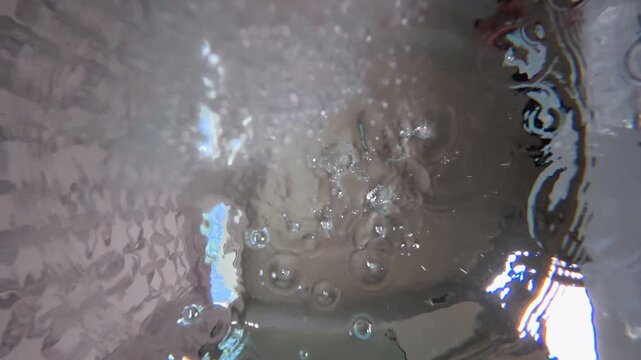 Underwater POV shows bath bombs being dropped into bathtub
