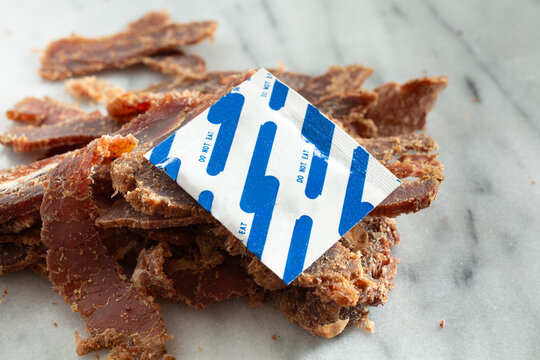 A view of a silica gel packet on a pile of steak jerky.