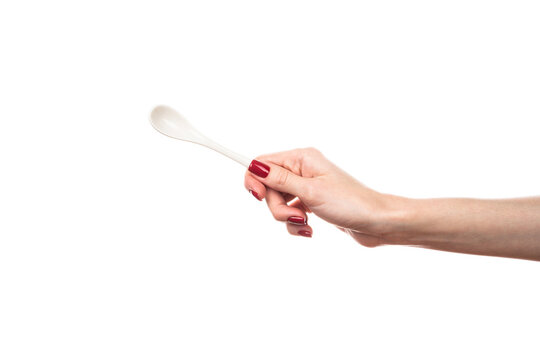 White ceramic tea spoon in female hand isolated on white background.