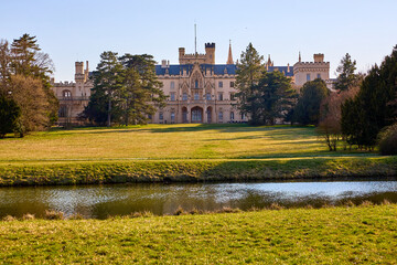 Obraz premium Elegant gothic revival castle with towers by a serene pond