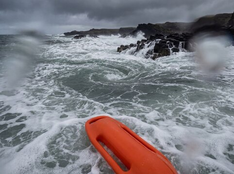 POV rescue tube approaching rip current near jagged rocks violent ocean surf extreme danger scene
