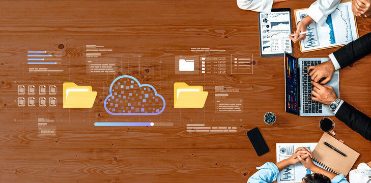 Above view of a business meeting featuring cloud technology. Participants analyze data on laptops, share ideas, and plan strategies for growth in a professional workspace. Ledger