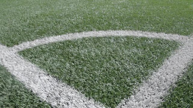 From the corner kick of a soccer field, the entire pitch is visible. The turf is synthetic, the lines marking the boundaries of the play area are white, and everything is seen with great clarity.