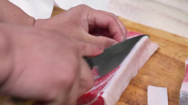close-up, high-angle shot of a professional sushi chef using a traditional long-bladed Yanagiba knife to precisely slice a block of highly marbled fatty tuna (Otoro).