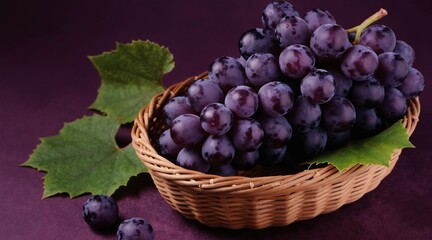 Naklejka premium Ripe purple grapes fill a woven basket. Green leaves and loose fruit rest nearby. Image styled as still life for food promotion on textured dark backdrop.