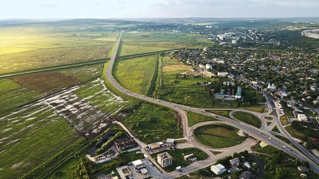 Aerial view showing car traffic on multilevel highway system with rural landscape and buildings.