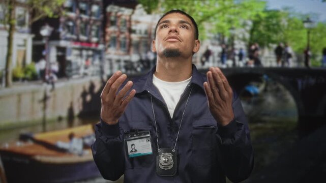 Man police investigator with badge and id, hands raised palms up looking skyward on a street; hope faith gratitude.