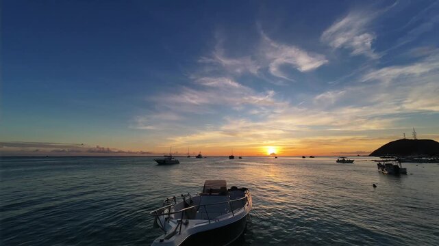 Peaceful sunset timelapse captures the serene beauty of Gran Roque, Los Roques, as silhouettes of boats drift across a vibrant Caribbean horizon.
