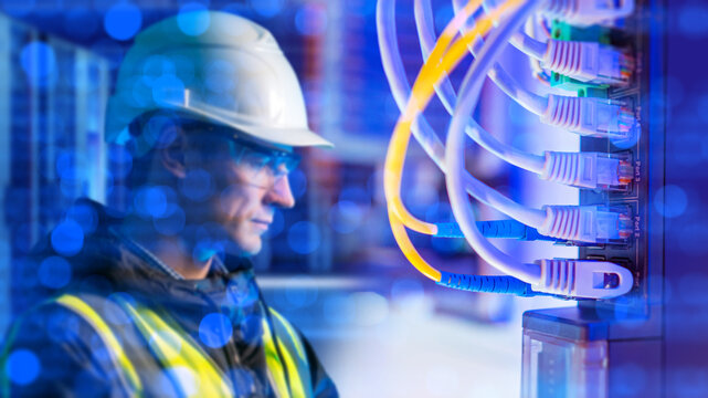 Data center networking. Technician monitors server rack cables and network ports during IT infrastructure maintenance.