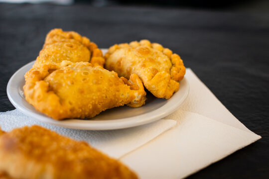 Primer plano de empanadas tradicionales fritas resaltando el repulgue artesanal y la masa burbujeante crujiente, con profundidad de campo reducida. Desenfoque.