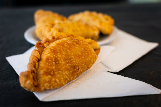 Foco selectivo en una empanada frita apoyada sobre servilletas de papel, con otras unidades desenfocadas en el fondo, ideal para men&uacute; de restaurante. Fotograf&iacute;a gastron&oacute;mica con bokeh.