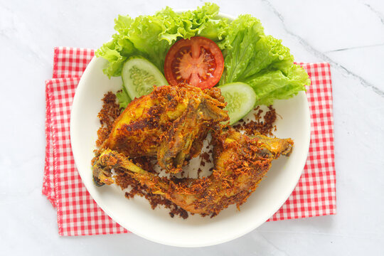 Top view of Yellow or Turmeric Fried Chicken served on a white plate with fresh vegetables.