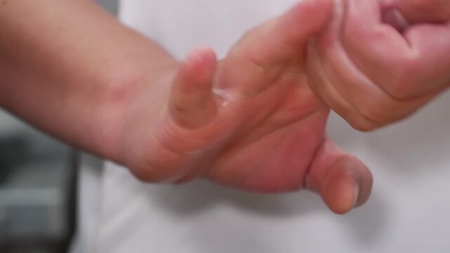 Close-up of a chef's expert hands molding freshly cooked, short-grain Japanese white rice into a traditional onigiri (rice ball) or nigiri shape. The footage captures the authentic culinary technique 