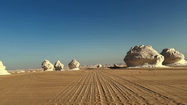 Pov off road car driving on sand between limestone rock formations in White Desert at sunset