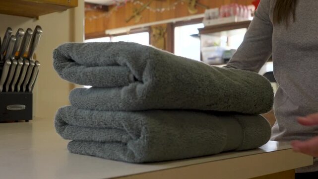 Folding soft cotton towels and placing them in a stack on the counter.