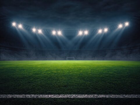 Vibrant green soccer field inside large stadium at night, brightly lit by powerful overhead floodlights creating dramatic beams of light. High quality photo