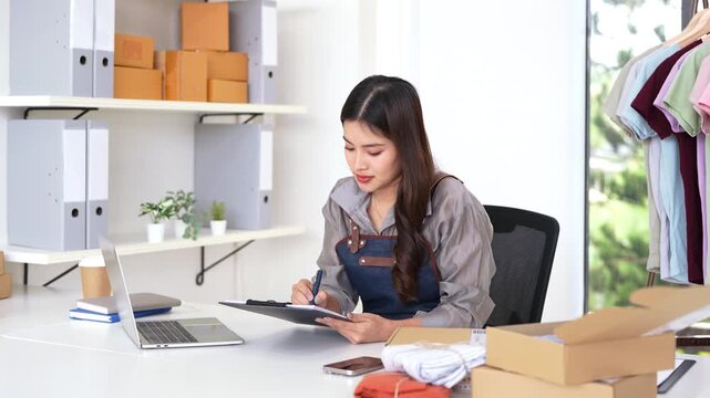 Startup small business owner working with computer at workplace. freelance seller check product order, packing goods for delivery to customer. Online selling, e-commerce, shipping concept