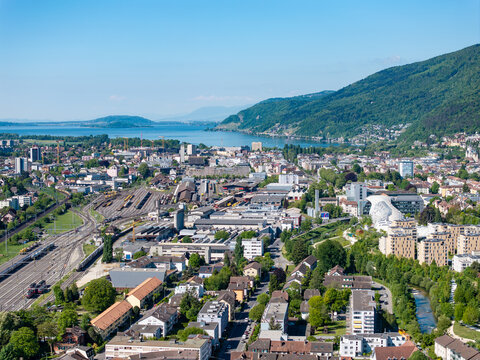 Aerial view of the industrial area and railway tracks near the city center with Lake Biel and lush green hills in the background Biel Bienne, Canton of Bern, Switzerland.