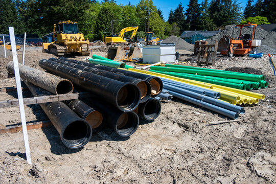 Stacks of sewar and water pipes, and electrical and telecommunication conduit, new residential development construction project in earthworks stage installing underground utilities
