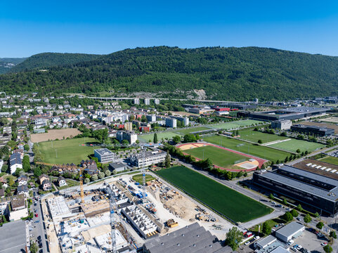 Aerial view of the industrial and residential area of Biel Bienne Bozingenfeld Champ featuring construction sites and sports fields under a clear blue sky in Biel Bienne, Canton of Bern, Switzerland.