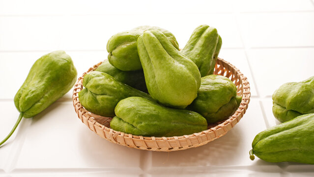 A pile of green chayote squash on bamboo plate