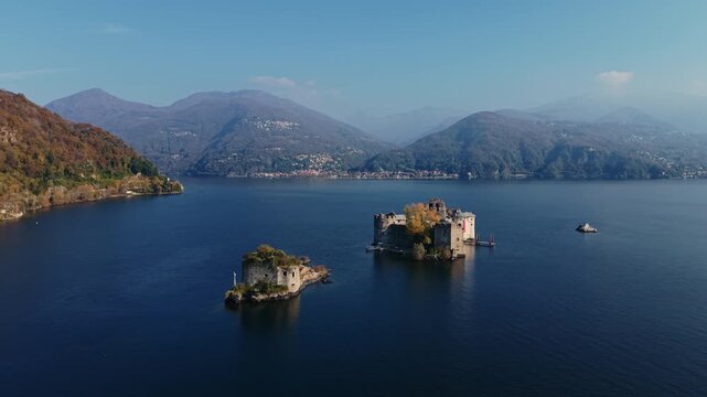 Aerial: Castelli di Cannero, three rocky islets, during the day with Lake Maggiore in northern Italy, Europe, pull out drone shot