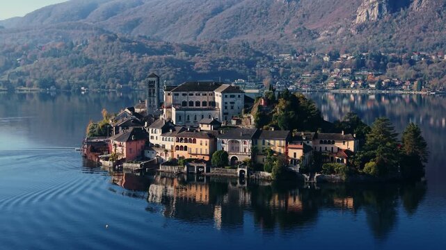 Aerial: close establishing drone shot of San Giulio Island and Basilica di San Giulio during the day in Piedmont, Italy, Europe