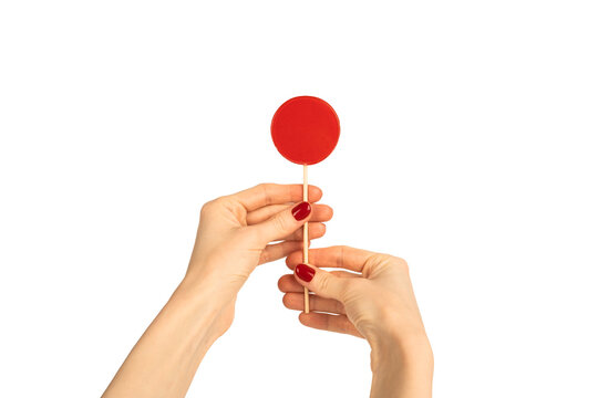Round lollipop in female hand isolated on white background. Red manicure. Chupa Chups.