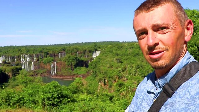 Male traveler photographing Iguazu Falls waterfall tropical rainforest scenic view.
