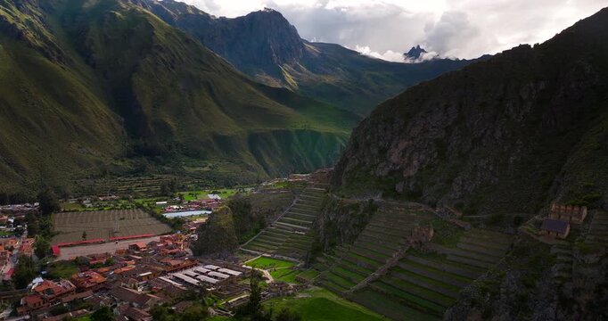 Aerial view of modern town of Ollantaytambo with its red roofs next to ancient Inca fortress and terraces in Sacred Valley, Peru