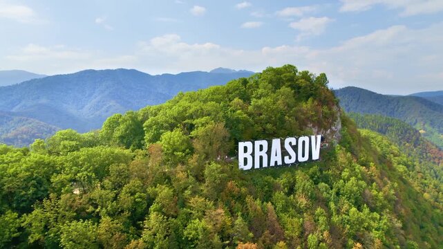 Aerial drone view of Brasov city sign on Tampa mountain in Romania showing scenic summer city landscape.