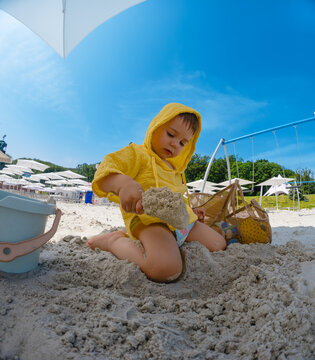 Toddler playing with sand on sunny beach.