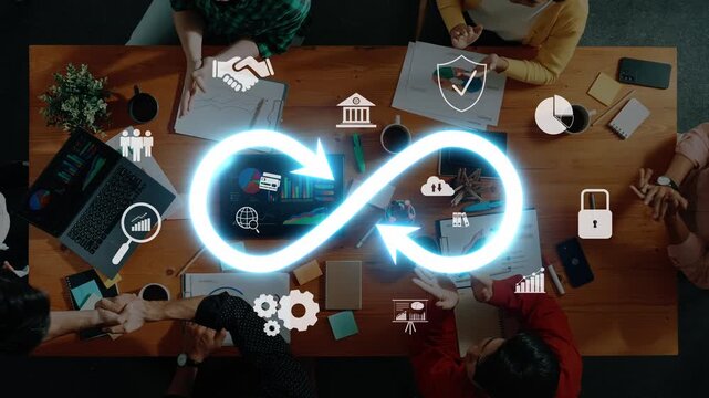An overhead view of a diverse group engaged in a collaborative business strategy meeting. An infinity loop graphic illustrates themes of growth and innovation. Raster