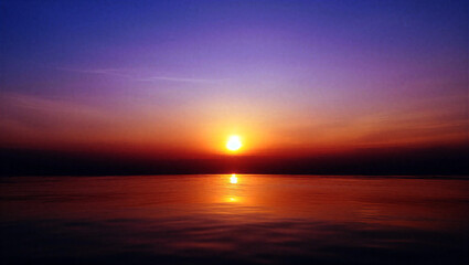 Obraz premium Stunning sunset over calm water with vibrant orange and purple sky colors creating a peaceful ambiance