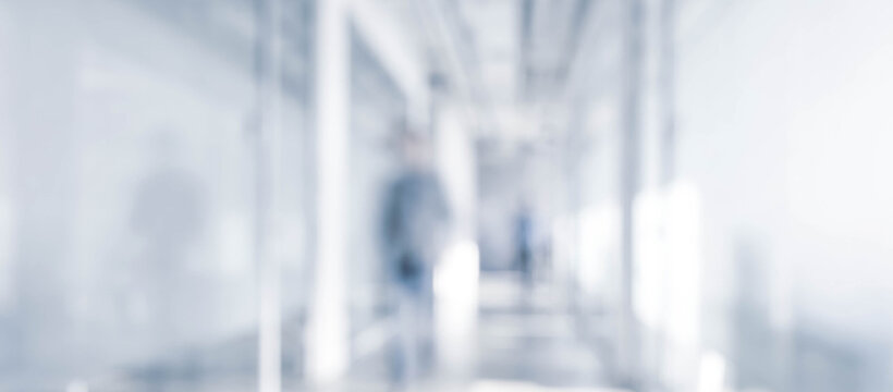 A blurred image of a corridor, featuring vague human figures in the distance. The bright, minimalistic environment conveys a sense of depth and perspective.