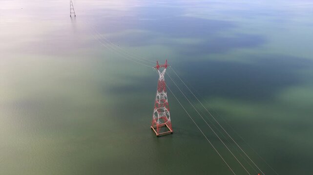 Power Transmission Towers Spanning River Under Cloudy Skies