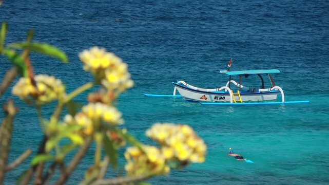Traditional Balinese Snorkeling diving boat floating on vibrant ocean waves in Bali