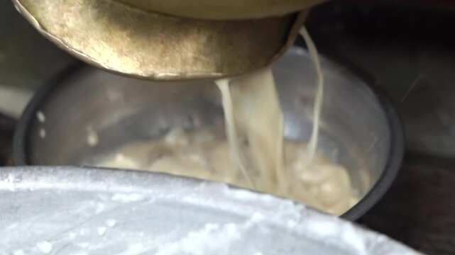 Extreme close up shot of making lassi from curd in vessel. Indian food preparation and dairy mixing process.