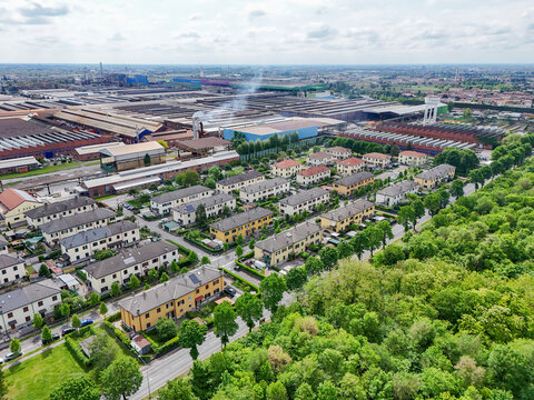Aerial view of the industrial complex and residential neighborhood with rows of houses and green trees in Dalmine, Lombardy, Italy.