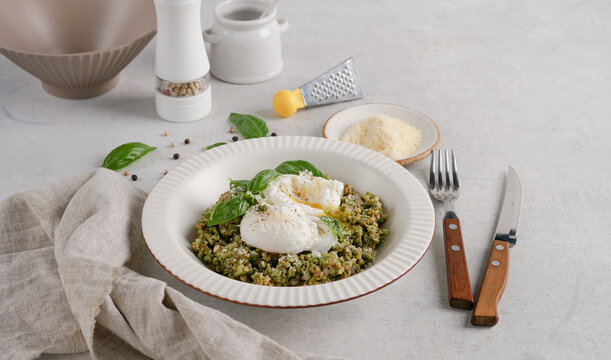 Buckwheat porridge with spinach pesto and poached eggs served on light table.